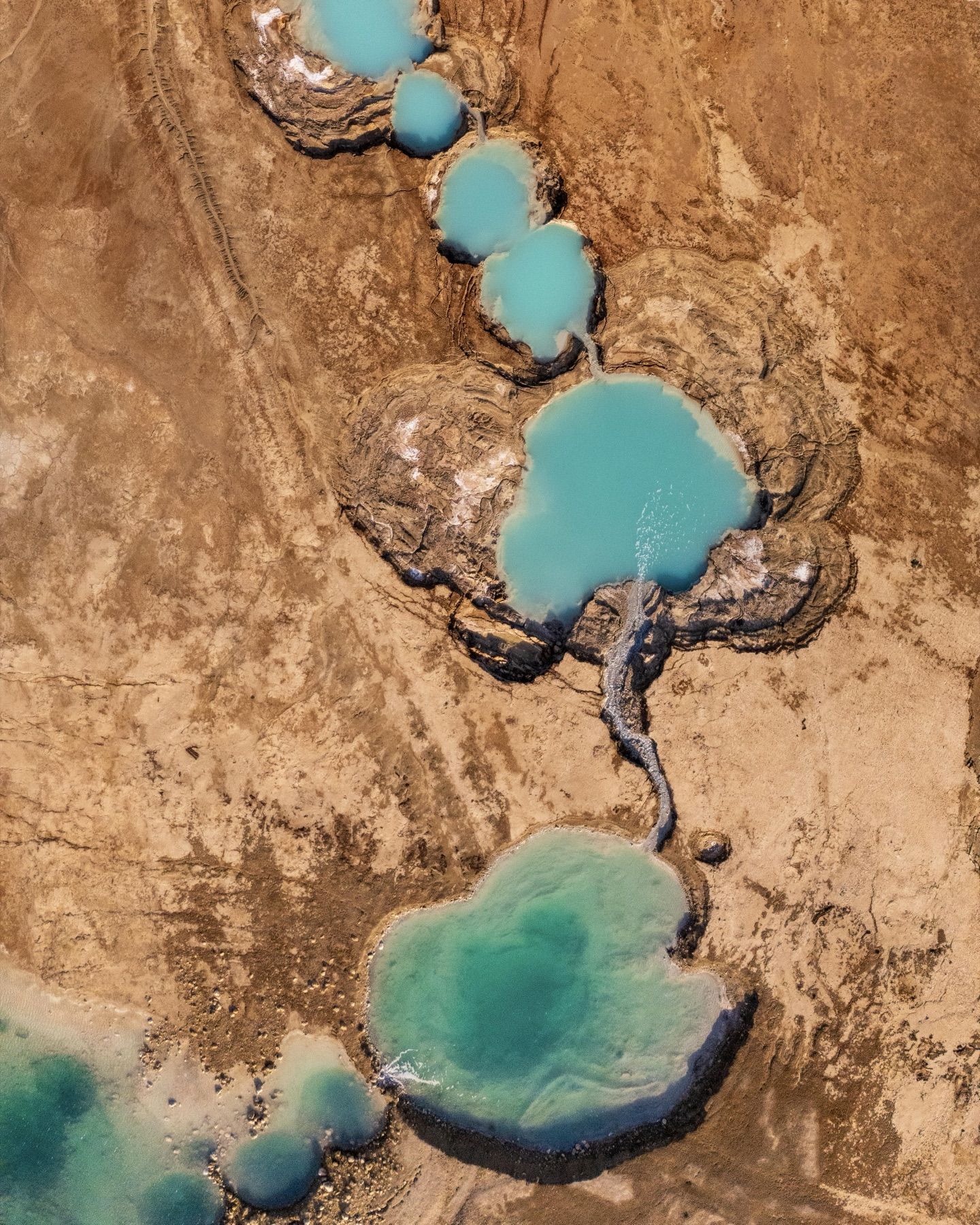 Turquoise salt pools in a desert basin, from above